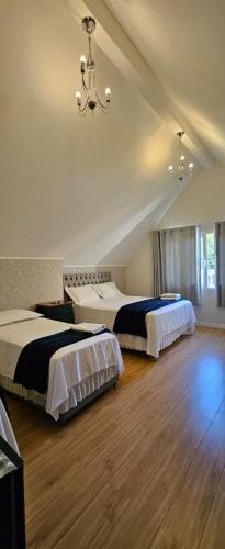 a bedroom with two beds and a chandelier at Pousada Behling Haus in Pomerode