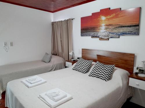 a bedroom with two beds and a painting on the wall at Alojamiento - Apart Hotel Libres - Hospedaje in Paso de los Libres