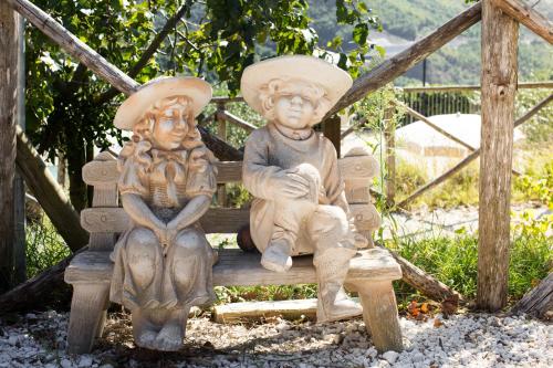 two statues of children sitting on a bench at Agriturismo La Coccinella in Valfabbrica