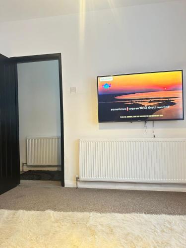 a flat screen tv hanging on a wall at Aldershot Spacious 3-Bedroom House with Fast Wi-Fi & Free Parking in Aldershot
