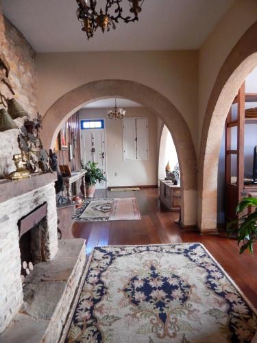 a large living room with a stone fireplace and a chandelier at Casa da Kau in Ouro Preto