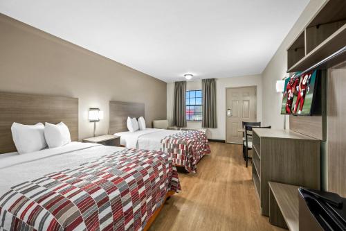 a hotel room with two beds and a flat screen tv at Red Roof Inn College Station in College Station