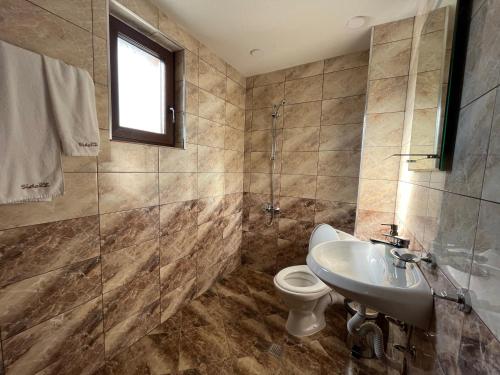 a bathroom with a toilet and a sink at Къща за гости - Вила Сидона in Banya