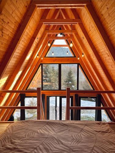 a room with a large window in a cabin at A Frames By Pensiunea Merișor in Răchiţele
