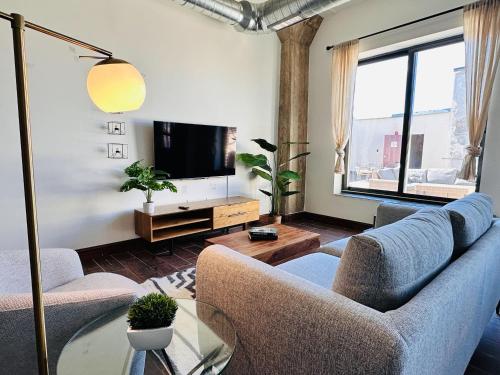 a living room with a couch and a tv at Sosuite at Independence Lofts - Callowhill in Philadelphia
