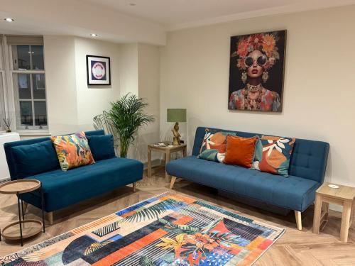 a living room with two blue couches and a painting at Heart of Brighton Apartment in Brighton & Hove