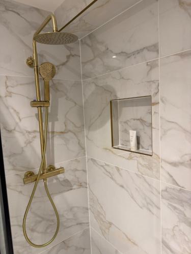 a shower with a gold shower head in a bathroom at Heart of Brighton Apartment in Brighton & Hove