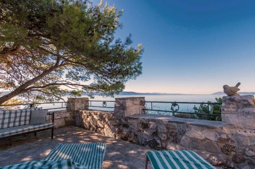 a patio with a bench and a view of the ocean at House Dobrila in Igrane