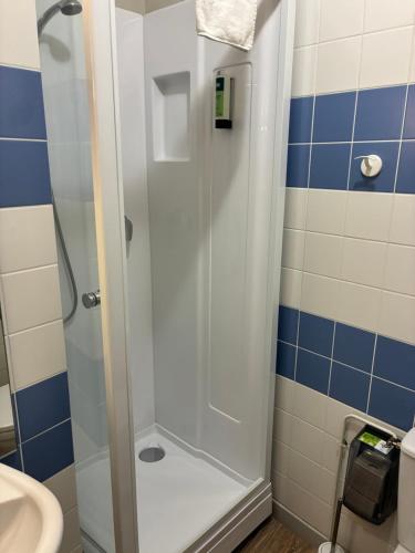 a shower stall in a bathroom with blue and white tiles at Logis Hôtel du Commerce in Volvic
