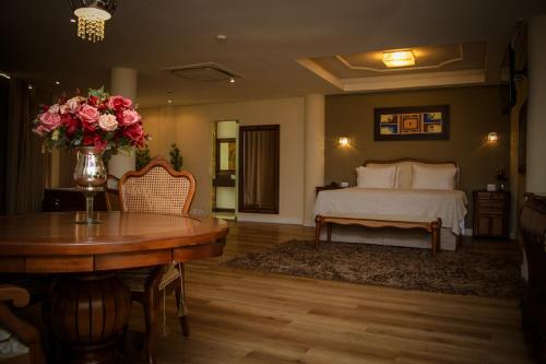 a bedroom with a bed and a table with a vase of flowers at Minas Platinum Hotel & Convention in Conselheiro Lafaiete