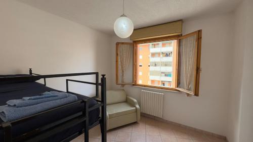 a bedroom with a bed and a window and a chair at Tre Archi Sea Home in Lido di Fermo