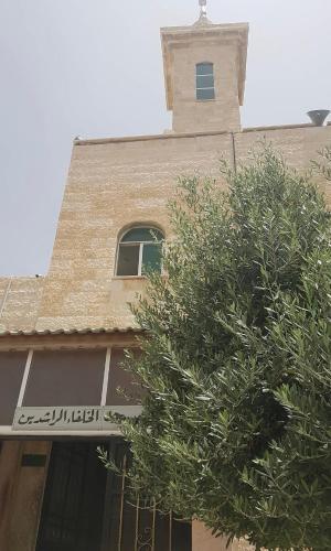 a building with a clock tower and a tree at Jalal House in Amman