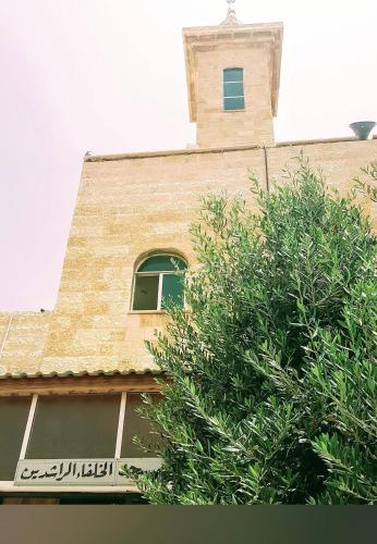 a building with a tower with a window and a tree at Jalal House in Amman