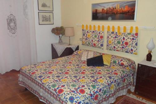 a bedroom with a bed with a colorful comforter at Villa Vallevento in Calamandrana