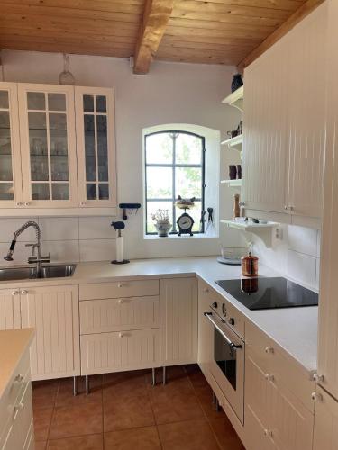 a kitchen with white cabinets and a sink and a window at Fårhuset at Åkarp in Trelleborg