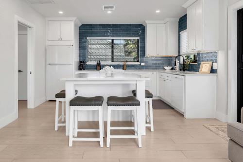 a kitchen with white cabinets and a white island with stools at Art Deco Apt w Pool One Mile to Beach Pets Welcome in Lake Worth