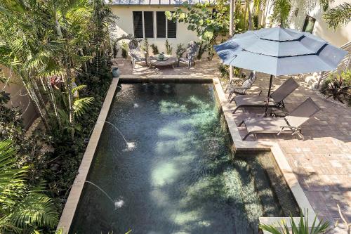 a swimming pool with an umbrella and a table and chairs at Art Deco Apt w Pool One Mile to Beach Pets Welcome in Lake Worth
