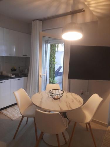 a dining room table with white chairs and a light at Nature Nest in Larisa