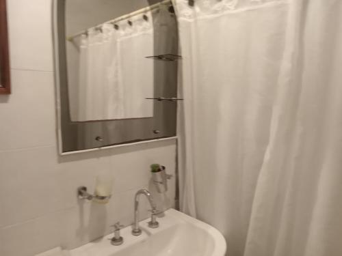 a bathroom with a white shower curtain and a sink at Nahomi House in Barrio Félix U Camet