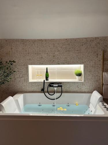 a bath tub with a bottle of wine in it at Suite Spa Cinta in Trie-Château