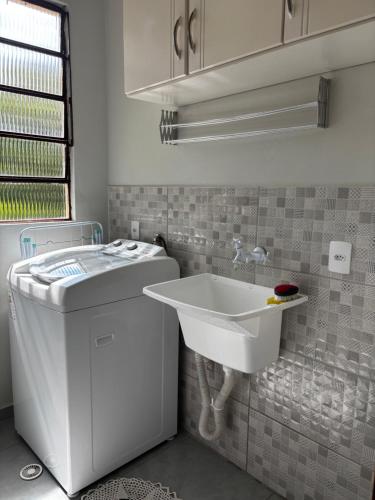 a white bathroom with a sink and a washing machine at Casa na Natureza Próx Pomerode e Timbó in Rio dos Cedros