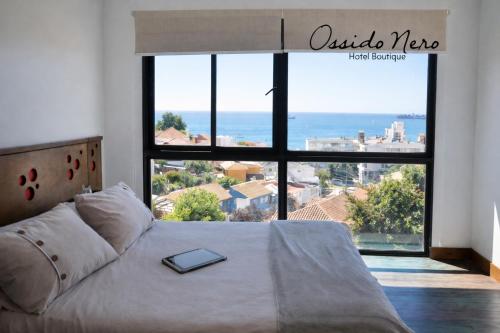 a bed with a book on it in front of a window at Hotel Boutique Ossido Nero in Viña del Mar