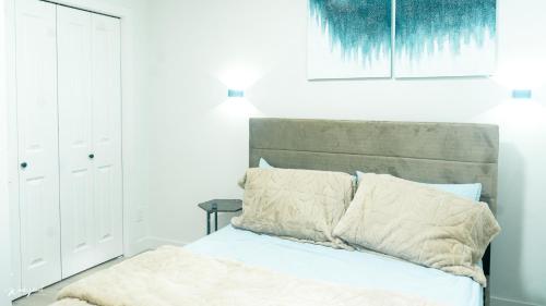 ein Schlafzimmer mit einem Bett und einem Gemälde an der Wand in der Unterkunft Ebenz Apartment in Calgary