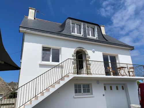 a white house with a balcony and stairs at Tall Ar Groas in Plogoff