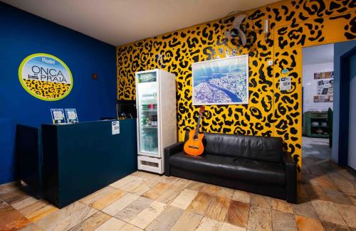 a room with a black couch and a yellow wall at Onça da Praia Hostel in Vitória