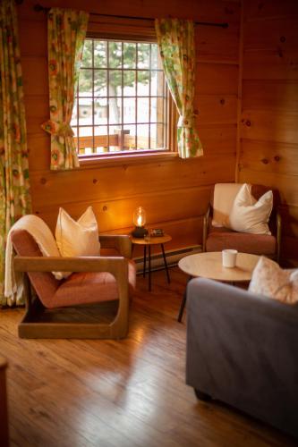 a living room with a couch and chairs and a window at Radium Cabins Centrally located in Radium Hot Springs BC in Radium Hot Springs