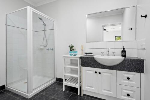 a white bathroom with a sink and a shower at Central Geelong Escape Spa, Fire Pit, Sleeps 10 in Geelong