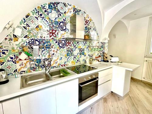 a kitchen with a sink and a mosaic wall at Trifoglio Apartment in Maiori
