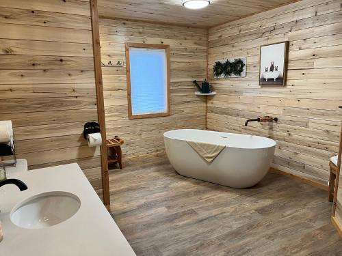 a bathroom with a large tub and wooden walls at Alaska Knotty Pine Whole Building in Palmer