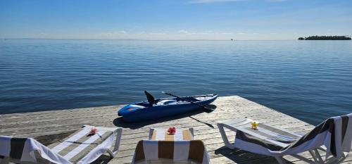 a blue boat on a dock with chairs and a table at Raiatea Sunrise villa in Taputapuapea