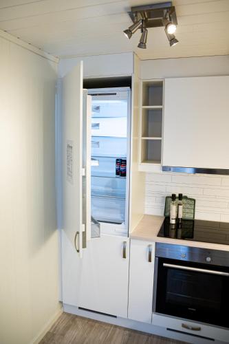 a kitchen with white cabinets and a refrigerator at Modern apartment near train station H77A in Narvik
