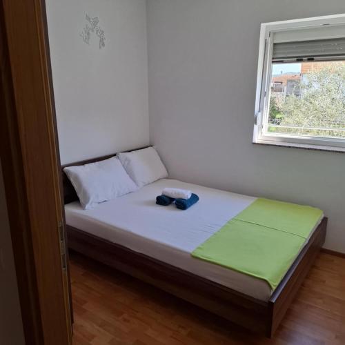 a small bed in a room with a window at Apartments Oliva - Maslina in Bilice