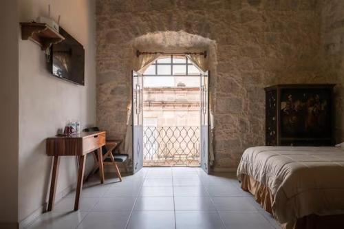 a bedroom with a bed and a table and a window at Casa Alzate in Morelia