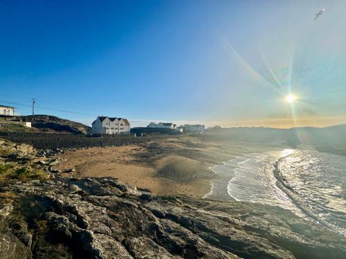 a beach with the sun rising over the ocean at GWYNFA-3 BED- GROUND FLOOR APT - SEA VIEWS - TREARDDUR BAY in Trearddur