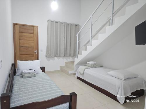 a bedroom with two beds and a staircase at Flor de Jagube Guest House in Ubatuba