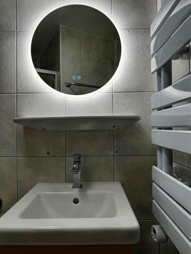 a bathroom with a sink and a round mirror at BEST VIEW Winterberg - Kleines Studio Apartment in Winterberg