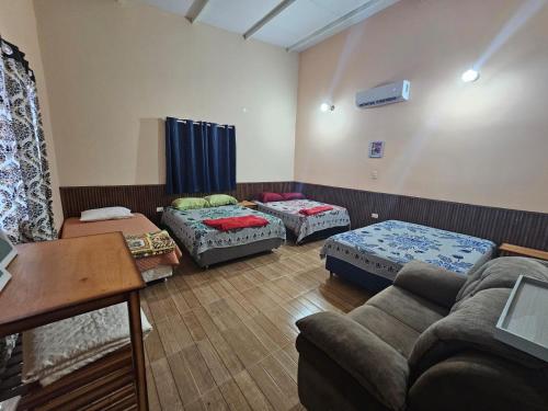 una sala de estar con tres camas y un sofá en Hospedaje 63, en Caacupé