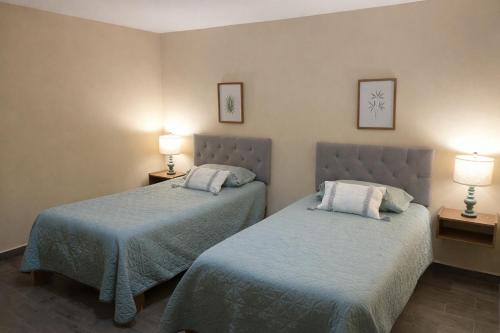 two beds in a hotel room with two lamps at Villa Ojo de Agua AIFA in Hacienda Ojo de Agua