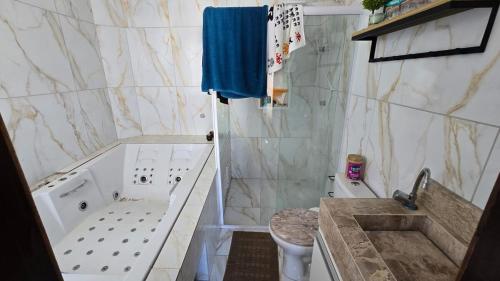 a bathroom with a tub and a toilet and a sink at Jacumã Gold in Conde
