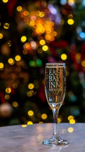 a wine glass sitting on a table with a christmas tree in the background at East Bay Inn, Historic Inns of Savannah Collection in Savannah