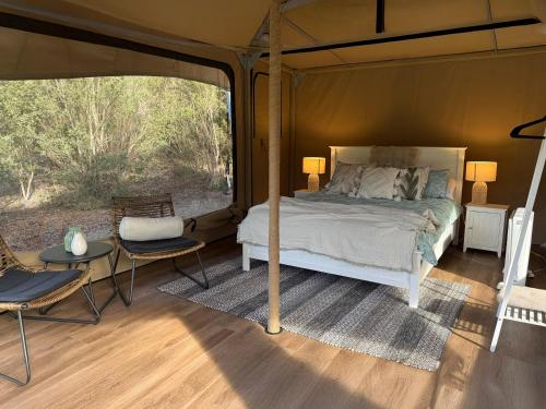 a bedroom in a tent with a bed and chairs at Ukiyo Nature Retreat in Fingal