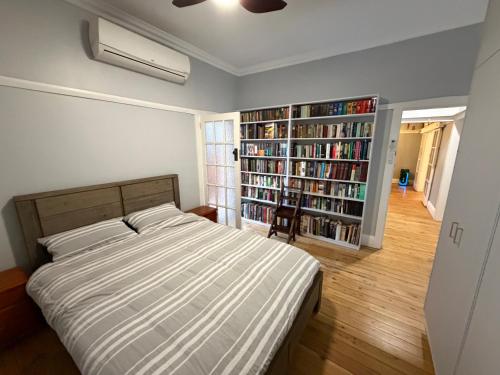 a bedroom with a bed and a book shelf with books at Tily's Place in Parkes