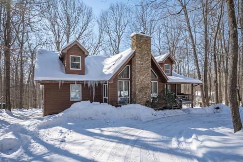 a house covered in snow in the woods at Get Your Creek On by Railey Vacations in Swanton