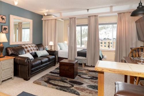 a living room with a leather couch and a bed at Snowblaze E102 Studio in Winter Park