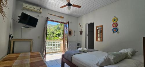 a bedroom with a bed and a television and a balcony at Pousada Encontro das Águas in Trindade