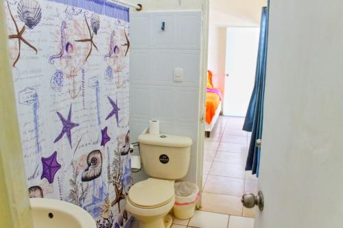 a bathroom with a toilet and a shower curtain at Casa Libre Guest House in Conchagua